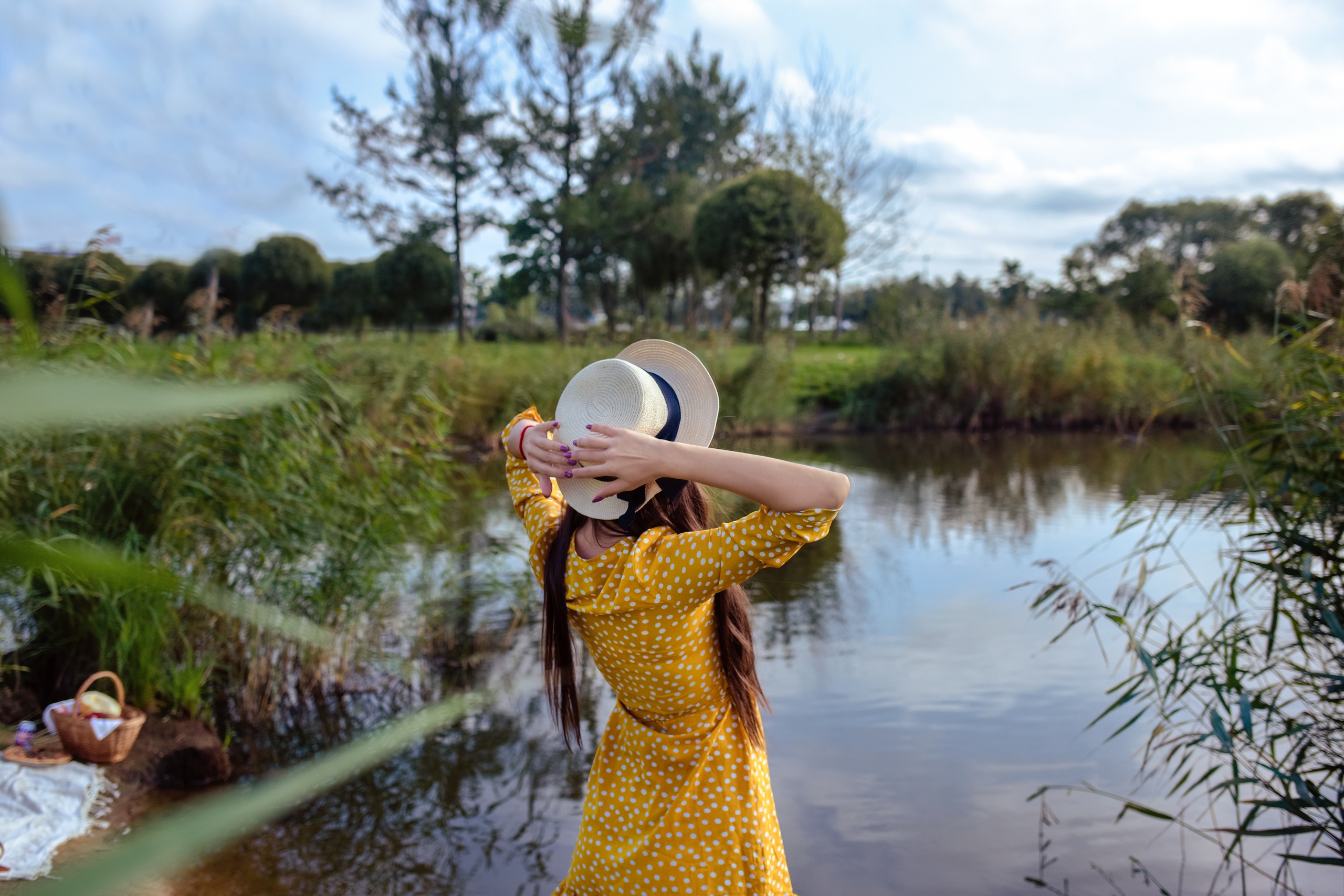 People 2560x1707 women model brunette dress yellow dress hat women with hats picnic baskets outdoors depth of field lagoon painted nails back women outdoors long hair water trees