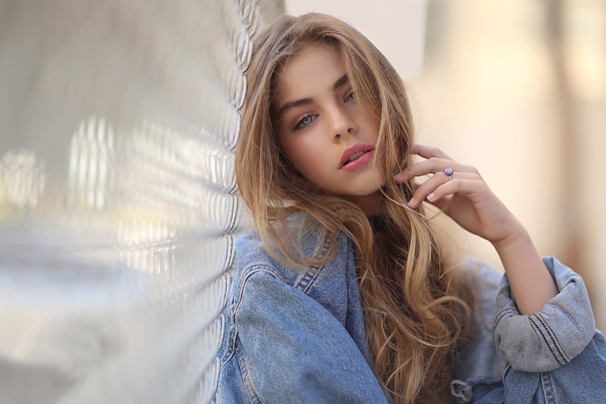 People 2000x1333 fence blonde face portrait women hair in face pink lipstick blue eyes open mouth denim jacket long hair looking at viewer one arm up messy hair jeans