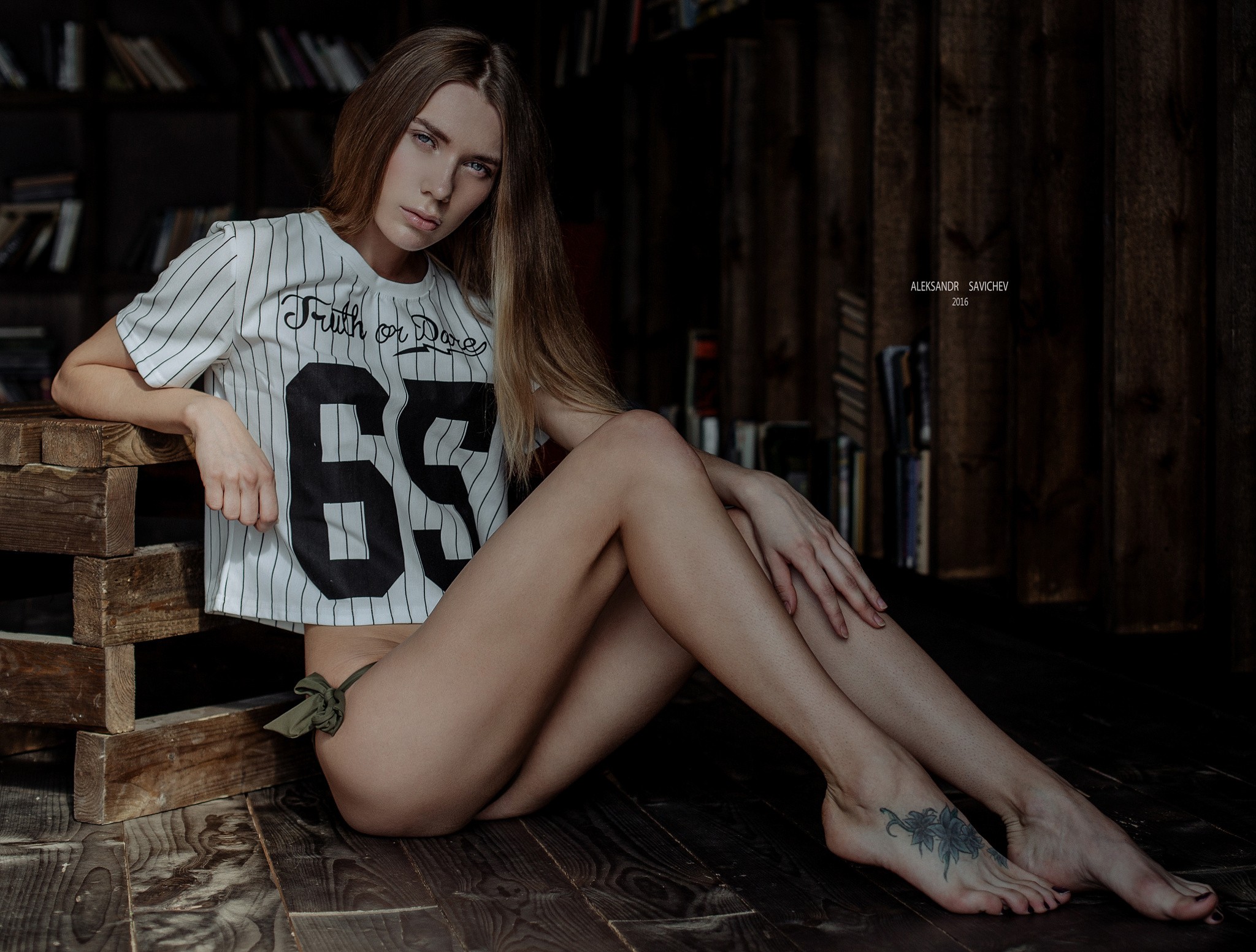 People 2048x1553 women tattoo skinny T-shirt long hair sitting wooden surface portrait Aleksandr Savichev feet printed shirts numbers women indoors model indoors looking at viewer 2016 (year)